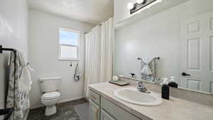 Full bathroom featuring a textured ceiling, toilet, baseboards, bathtub and shower, tile finish floor, and vanity