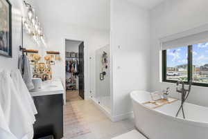 Full bathroom with a soaking tub, a stall shower, a spacious closet, tile patterned flooring, and vanity