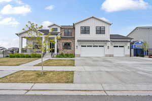 View of front facade featuring board and batten siding, a front lawn, concrete driveway, and fence