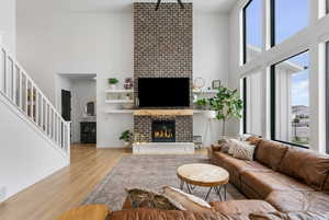 Living room with stairs, wood finished floors, a high ceiling, a fireplace, and baseboards