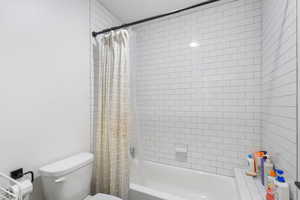 Full bath featuring toilet and shower / bath combo with shower curtain