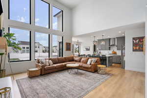 Living area with light wood finished floors, baseboards, and a high ceiling