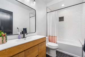 Full bathroom with vanity, recessed lighting, shower / bathtub combination with curtain, and toilet