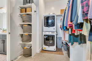 Washroom with stacked washer and dryer, baseboards, visible vents, and laundry area