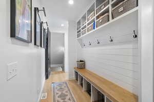 Mudroom with a barn door, light wood finished floors, baseboards, visible vents, and recessed lighting