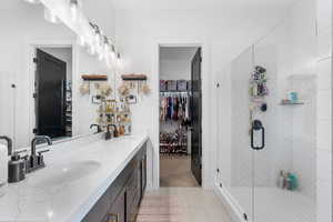 Full bath featuring tile patterned floors, a sink, double vanity, and a stall shower