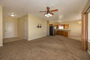 Unfurnished living room with light carpet, baseboards, light tile patterned floors, and ceiling fan