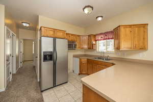 Kitchen with light countertops, light tile patterned flooring, stainless steel appliances, and a sink