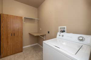Laundry room with washer / dryer, light tile patterned flooring, laundry area, and baseboards