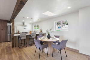 Dining room with recessed lighting, wood finished floors, beam ceiling, and a skylight