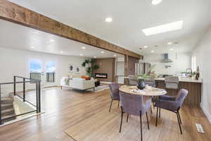 Dining space with baseboards, recessed lighting, a skylight, wood finished floors, and a large fireplace
