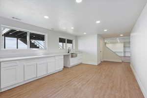 Kitchen with a sink, light wood finished floors, baseboards, visible vents, and recessed lighting