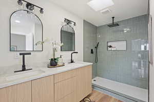Bathroom featuring a sink, a walk in shower, and double vanity