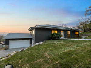 View of front of home featuring a garage, a yard, driveway, and a shingled roof