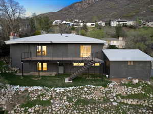 Back of property featuring a chimney, a yard, stairs, and a deck with mountain view