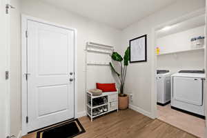 Laundry area with light wood-style floors, washing machine and clothes dryer, baseboards, and laundry area