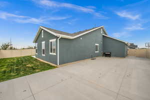 View of side of property with a gate, a patio area, fence, a yard, and stucco siding