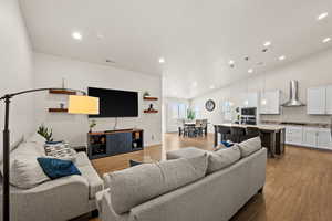 Living room with recessed lighting, light wood finished floors, visible vents, baseboards, and high vaulted ceiling
