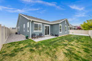Back of property featuring a lawn, a patio, a fenced backyard, and stucco siding