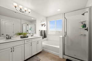 Bathroom featuring tile patterned floors, a sink, a stall shower, a bath, and double vanity
