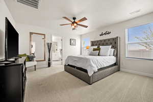 Bedroom with baseboards, light carpet, visible vents, and ensuite bathroom