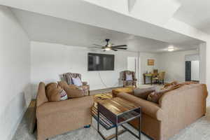Carpeted living area featuring a ceiling fan and baseboards