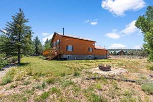 Rear view of property featuring stairway, central air condition unit, a lawn, a fire pit, and a deck