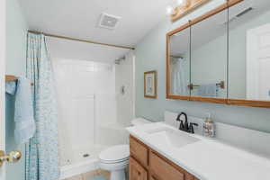 Full bathroom with toilet, a shower with curtain, vanity, and visible vents