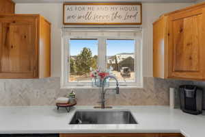 Kitchen with light countertops, brown cabinetry, decorative backsplash, and a sink