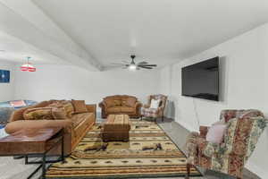 Carpeted living room with a ceiling fan and baseboards