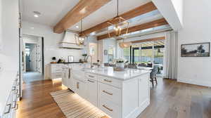 Kitchen with light wood finished floors, beam ceiling, a sink, and a notable chandelier
