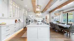 Kitchen featuring beam ceiling, a sink, light wood-type flooring, backsplash, and a chandelier