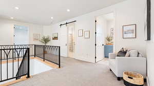 Sitting room featuring recessed lighting, carpet, an upstairs landing, and a barn door