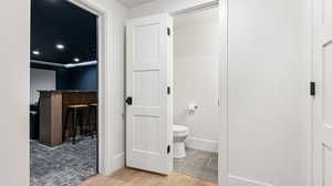 Bathroom featuring baseboards, wood finished floors, and toilet