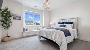 Bedroom with baseboards, visible vents, light colored carpet, and a notable chandelier