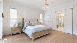 Bedroom with light wood-type flooring, visible vents, a notable chandelier, and ornamental molding