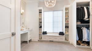 Spacious closet with light colored carpet, a notable chandelier, and visible vents