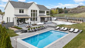 Back of property with a patio area, a fenced backyard, an outdoor structure, a fenced in pool, and a storage unit