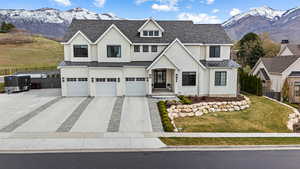 View of front of house featuring a standing seam roof, a mountain view, driveway, metal roof, and fence