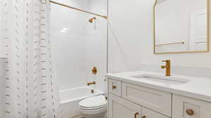 Full bath featuring shower / bath combo, vanity, and toilet