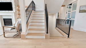 Stairs featuring a glass covered fireplace, wood finished floors, and baseboards