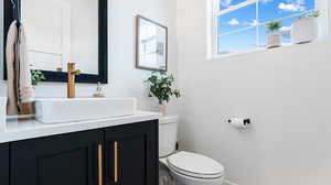 Bathroom with toilet, vanity, and baseboards