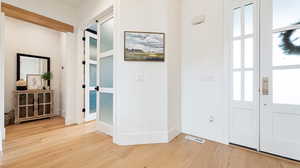 Entryway with light wood-type flooring, baseboards, visible vents, and a healthy amount of sunlight