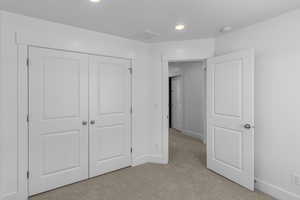 Unfurnished bedroom featuring recessed lighting, visible vents, a closet, baseboards, and light colored carpet
