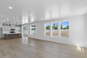 Unfurnished living room featuring baseboards, light wood-style flooring, and recessed lighting