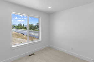 Carpeted spare room featuring baseboards, visible vents, recessed lighting, and a mountain view