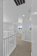 Hall with a textured ceiling, an upstairs landing, carpet flooring, visible vents, and recessed lighting