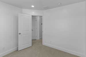 Spare room featuring recessed lighting, light carpet, and baseboards