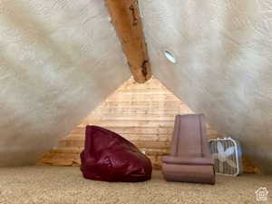 Interior space featuring vaulted ceiling with beams, wooden walls, and carpet flooring