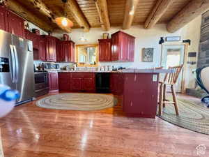 Kitchen featuring light wood finished floors, stainless steel appliances, wooden ceiling, and reddish brown cabinets